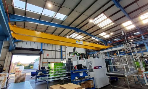 Overhead crane rated to 10,000kg spanning a manufacturing floor with injection moulding machinery